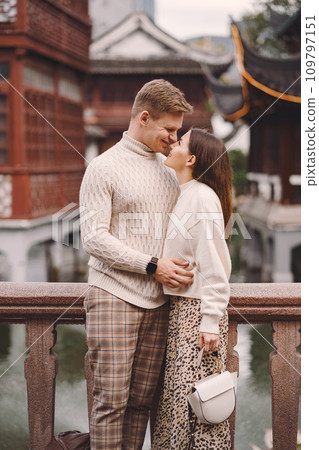 newlywed couple showing affection in Shanghai near Yuyuan. Couple take a break for some hugs while visiting China. husband and wife holding hands on the street by a market and pagoda newlywed couple showing affection in Shanghai near Yuyuan. Couple take a break for some hugs while visiting China. husband and wife holding hands on the street by a market and pagoda 109797151