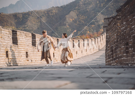 beautiful young couple running and jumping at the Great Wall of China. Newly married couple on their honemoon to Great Wall near Beijing China. Stylish couple exploring one of the wonders of the world beautiful young couple running and jumping at the Great Wall of China. Newly married couple on their honemoon to Great Wall near Beijing China. Stylish couple exploring one of the wonders of the world 109797168