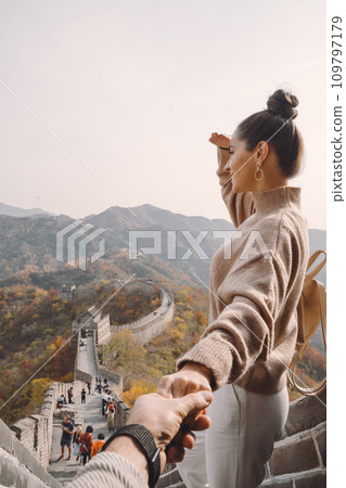 beautiful girl holding her husband's hand at the Great Wall of China. Newly married couple on their honemoon to Great Wall near Beijing China. Stylish couple exploring one of the wonders of the world beautiful girl holding her husband's hand at the Great Wall of China. Newly married couple on their honemoon to Great Wall near Beijing China. Stylish couple exploring one of the wonders of the world 109797179
