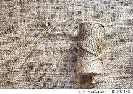 Skeins of thread on burlap. Yellow threads on coarse cloth. Skeins of thread on burlap. Yellow threads on coarse cloth. 109797428