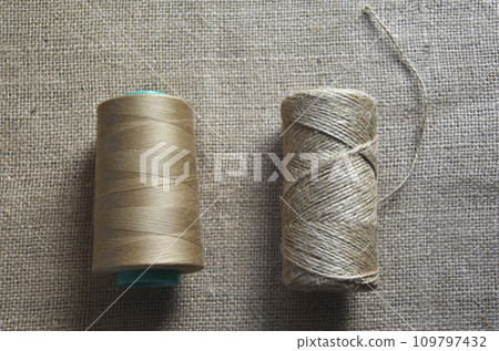 Skeins of thread on burlap. Yellow threads on coarse cloth. 109797432