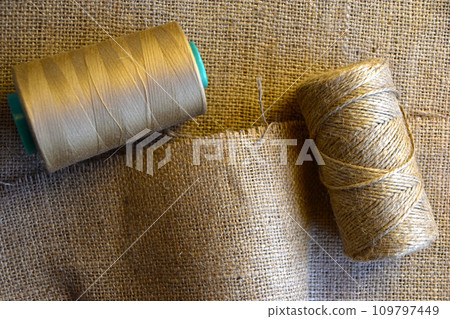 Skeins of thread on crumpled burlap. Yellow threads on coarse cloth. The material for the bags. Skeins of thread on crumpled burlap. Yellow threads on coarse cloth. The material for the bags. 109797449
