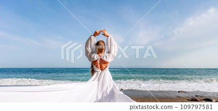 Woman beach white dress flying on Wind. Summer Vacation. A happy woman takes vacation photos to send to friends. 109797581