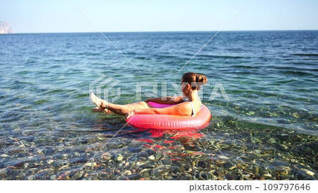Summer vacation happy woman floats on an inflatable donut mattress, pink swim ring. Summer travel holidays vacation on the sea. 109797646