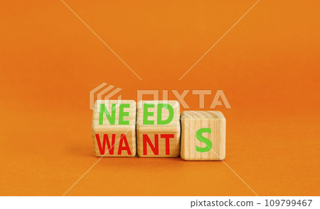 Wants or needs symbol. Turned wooden cubes and changed the word wants to needs. Beautiful orange table, orange background, copy space. Business and wants or needs want need concept. 109799467