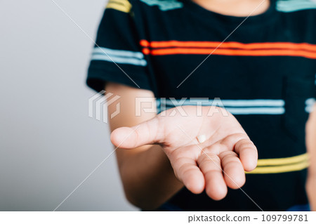 Happy little boy holds a fallen baby tooth symbolizing the hygiene of baby teeth. Hand showing first tooth lost reflecting child's development. Children show teeth new gap, dentist problems 109799781