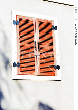 Vintage window latches or metal shutter hook or window hook mounted on red windows. 109800003