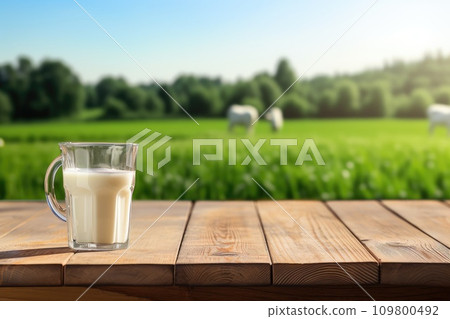 Empty wooden table with cheese and glass of milk. Cows grazing in the meadow in the background. Natural stage, background suitable for products or products for presentation Empty wooden table with cheese and glass of milk. Cows grazing in the meadow in the background. Natural stage, background suitable for products or products for presentation 109800492