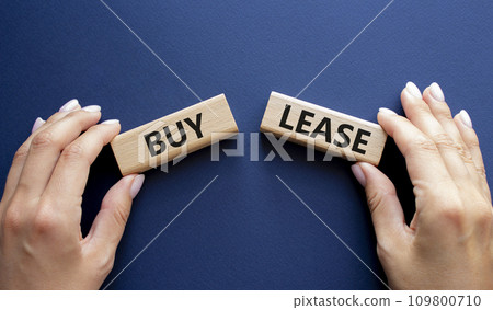 Buy or Lease symbol. Concept word Buy or Lease on wooden blocks. Businessman hand. Beautiful deep blue background. Business and Buy or Lease concept. Copy space Buy or Lease symbol. Concept word Buy or Lease on wooden blocks. Businessman hand. Beautiful deep blue background. Business and Buy or Lease concept. Copy space 109800710
