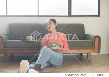 woman eating salad in the living room woman eating salad in the living room 109800900