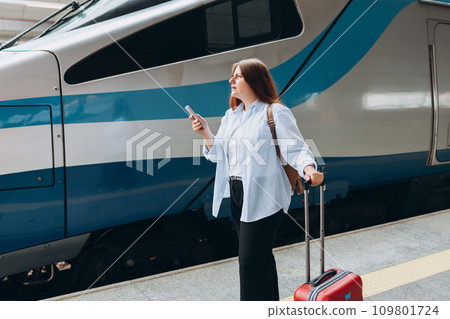 Young worried woman traveler with small backpack on the railway station, 30s redhead women waiting for train. Tourism, solo vacation Young worried woman traveler with small backpack on the railway station, 30s redhead women waiting for train. Tourism, solo vacation 109801724