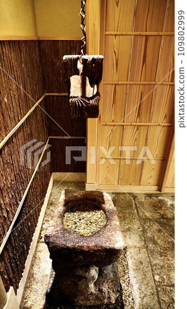 A stone mill indoors and a pestle hanging from the ceiling A stone mill indoors and a pestle hanging from the ceiling 109802999