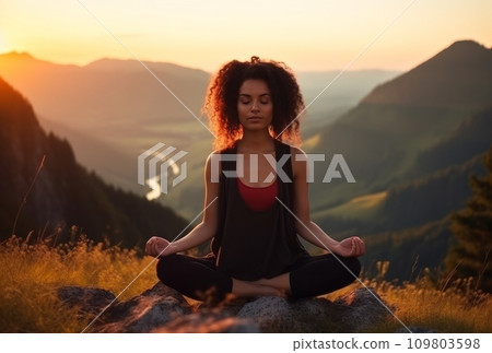 the woman is meditating at sunset on the top of a mountain the woman is meditating at sunset on the top of a mountain 109803598