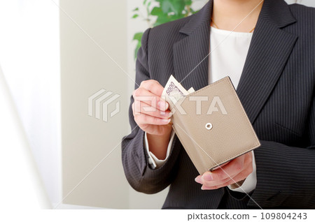 A woman checking the contents of her wallet A woman checking the contents of her wallet 109804243