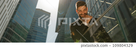 Handsome businessman with laptop standig on office terrace on skyscapers background 109804329