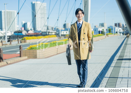 A young man in a suit walking in the winter city 109804758