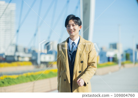 A young man in a suit walking in the winter city 109804760