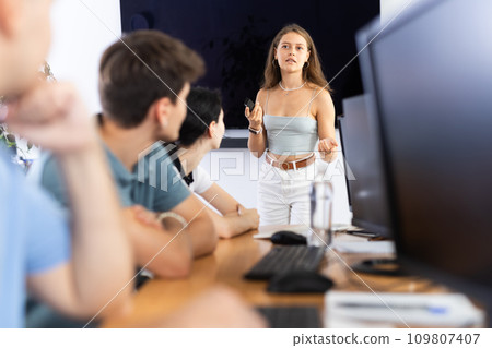 Young girl speaker stands in front of students and talks about use of artificial intelligence Young girl speaker stands in front of students and talks about use of artificial intelligence 109807407