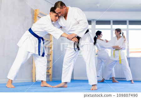 Middle-aged and young men applying throwing technique during judo classes Middle-aged and young men applying throwing technique during judo classes 109807490