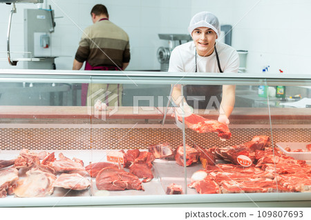 Guy who works in meat department of supermarket shows piece of beef Guy who works in meat department of supermarket shows piece of beef 109807693