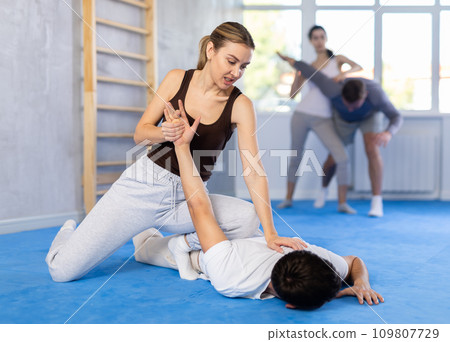 Young woman and guy training self-defense techniques Young woman and guy training self-defense techniques 109807729