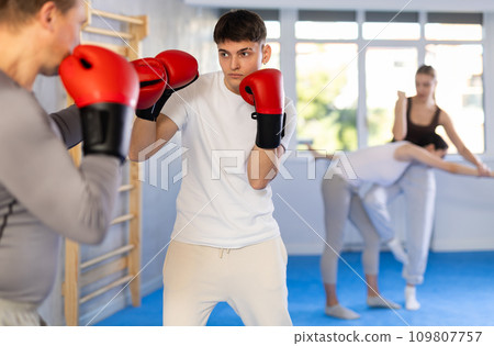 Two boxers in sportswear are engaged in boxing sparring in gym Two boxers in sportswear are engaged in boxing sparring in gym 109807757
