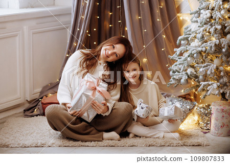 Mother and daughter opening Christmas gifts. Mother and daughter opening Christmas gifts. 109807833