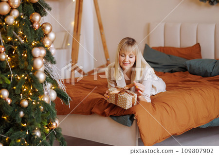 Woman with gift on bed at Christmas Woman with gift on bed at Christmas 109807902