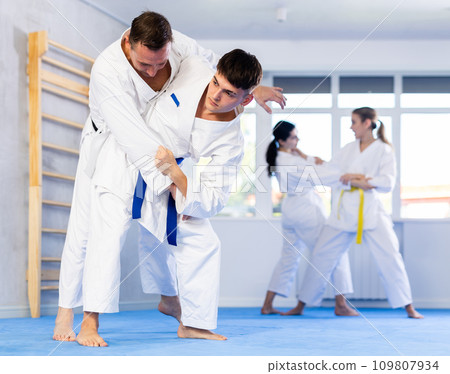 Middle-aged and young men applying throwing technique during judo classes Middle-aged and young men applying throwing technique during judo classes 109807934