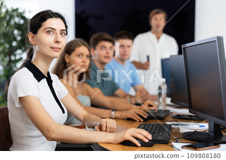 Students of computer courses sit in class near PC, watch to teacher and listen to lecturer Students of computer courses sit in class near PC, watch to teacher and listen to lecturer 109808180