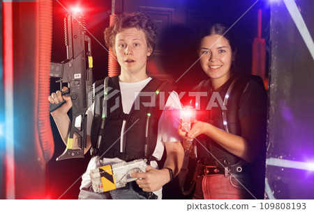 Boy and girl posing with lasertag guns in arena 109808193