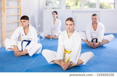 Young woman wearing kimono practicing butterfly position in sports hall 109808206