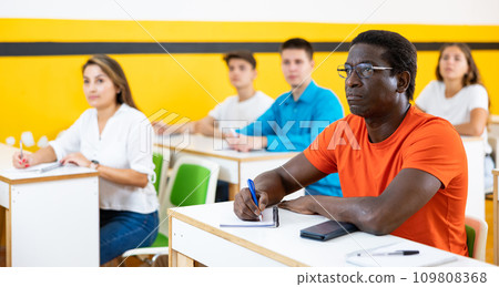 Multiethnic group of people studying together at tables. Focus on African american man 109808368