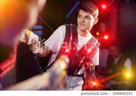 Portrait of positive man with laser gun having fun with her friends on lasertag arena Portrait of positive man with laser gun having fun with her friends on lasertag arena 109808381