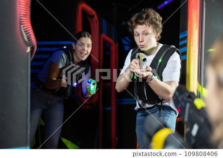 Two players guy and woman with laser weapons in dark laser tag room Two players guy and woman with laser weapons in dark laser tag room 109808406