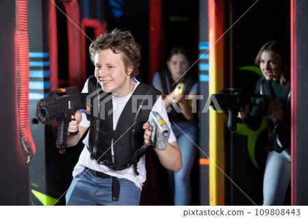 Excited teenager having fun playing lasertag in arena Excited teenager having fun playing lasertag in arena 109808443