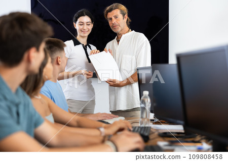 Male manager of IT startup giving contract to young woman Male manager of IT startup giving contract to young woman 109808458