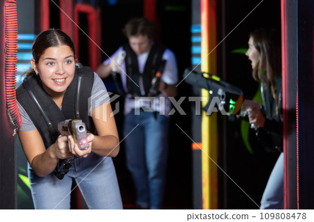 Girl running and dodging while playing lasertag 109808478