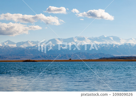 Blue calm water in Issyk-Kul lake with mountains on background at summer day 109809026