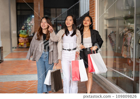Young happy Asian girls are spending their weekend in the city together, enjoying shopping day. 109809826
