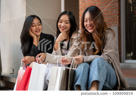 A group of happy female friends are resting on the stairs after enjoying their shopping day together 109809859