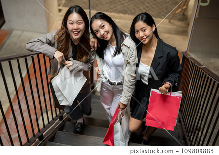 A group of attractive Asian female friends are carrying shopping bags, enjoying shopping together. A group of attractive Asian female friends are carrying shopping bags, enjoying shopping together. 109809883