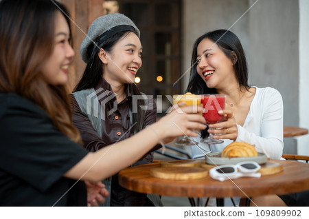 A group of trendy, happy Asian girls are drinking and enjoying talking in a cafe in the city. A group of trendy, happy Asian girls are drinking and enjoying talking in a cafe in the city. 109809902