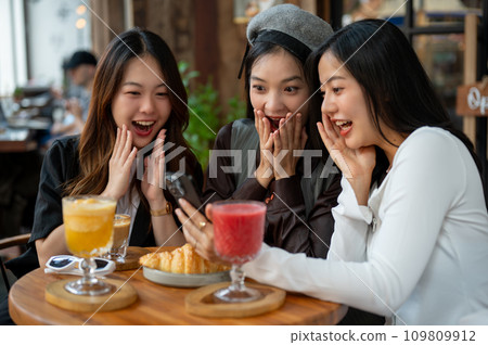 Group of attractive Asian female friends are enjoying talking in a cafe or restaurant, hanging out. 109809912