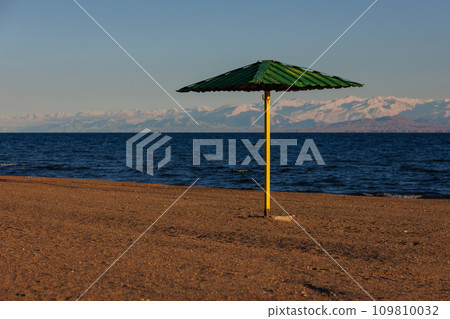 rigid steel umbrella on beach of mountain lake at sunny evening 109810032