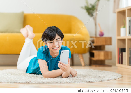 A woman who operates a smartphone in the living room. 109810735