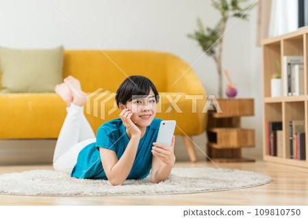 一個在客廳裡操作智能手機的女人。 109810750