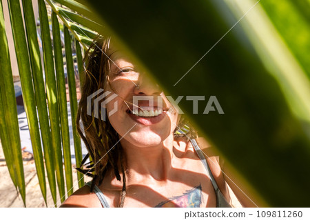 Smiling woman taking selfie under palm leaf on tropical beach. Summery vacations moment. Smiling woman taking selfie under palm leaf on tropical beach. Summery vacations moment. 109811260