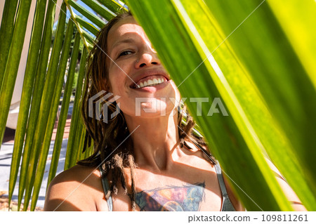 Smiling woman taking selfie under palm leaf on tropical beach. Summery vacations moment. Smiling woman taking selfie under palm leaf on tropical beach. Summery vacations moment. 109811261