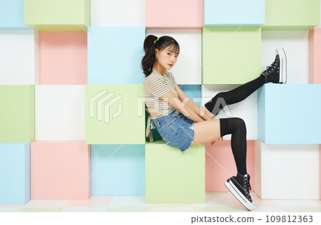 Casual portrait of a young woman photographed against a colorful background 109812363